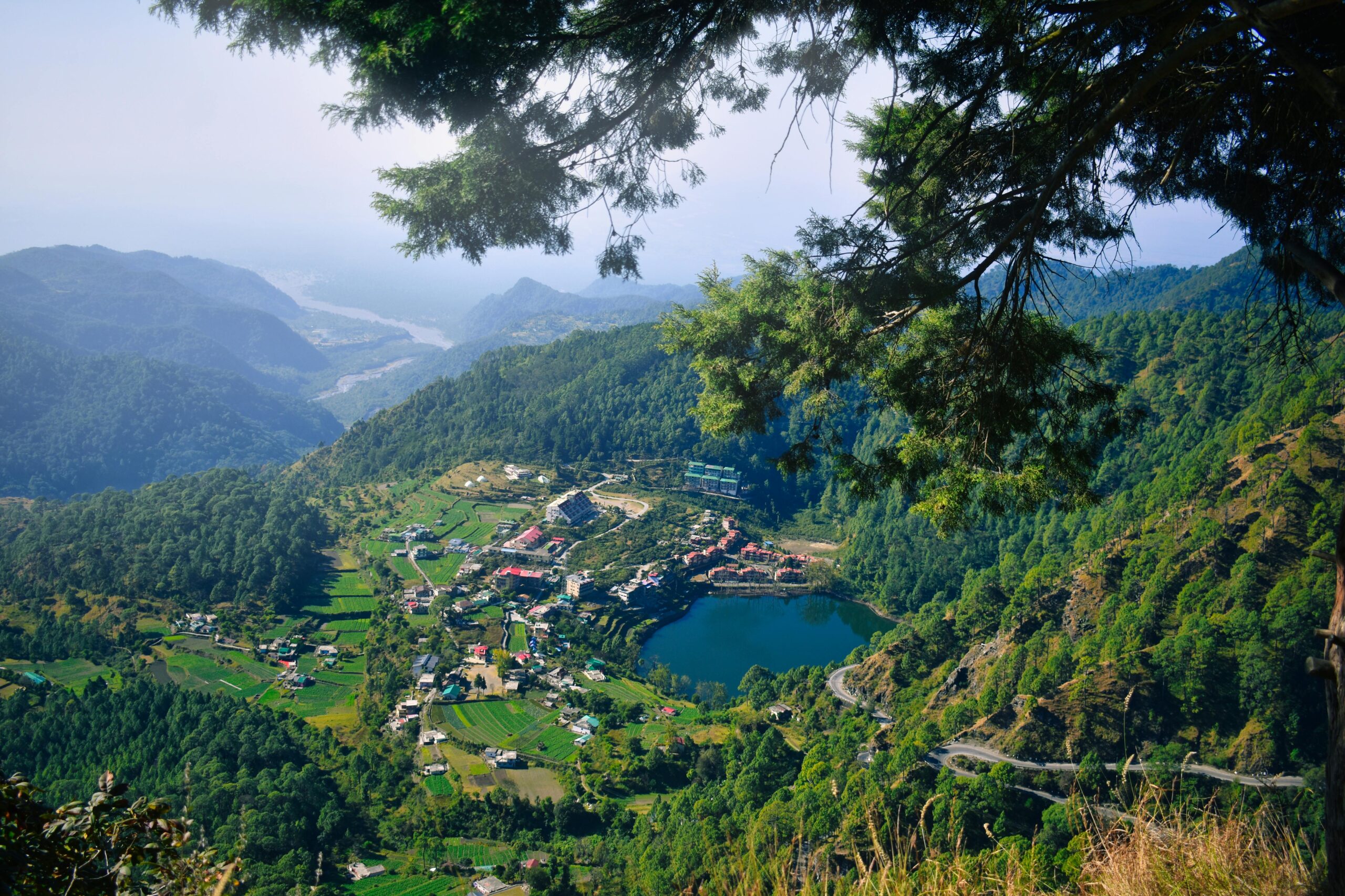 A stunning aerial view of Nainital town and lake surrounded by lush mountains and forest.
